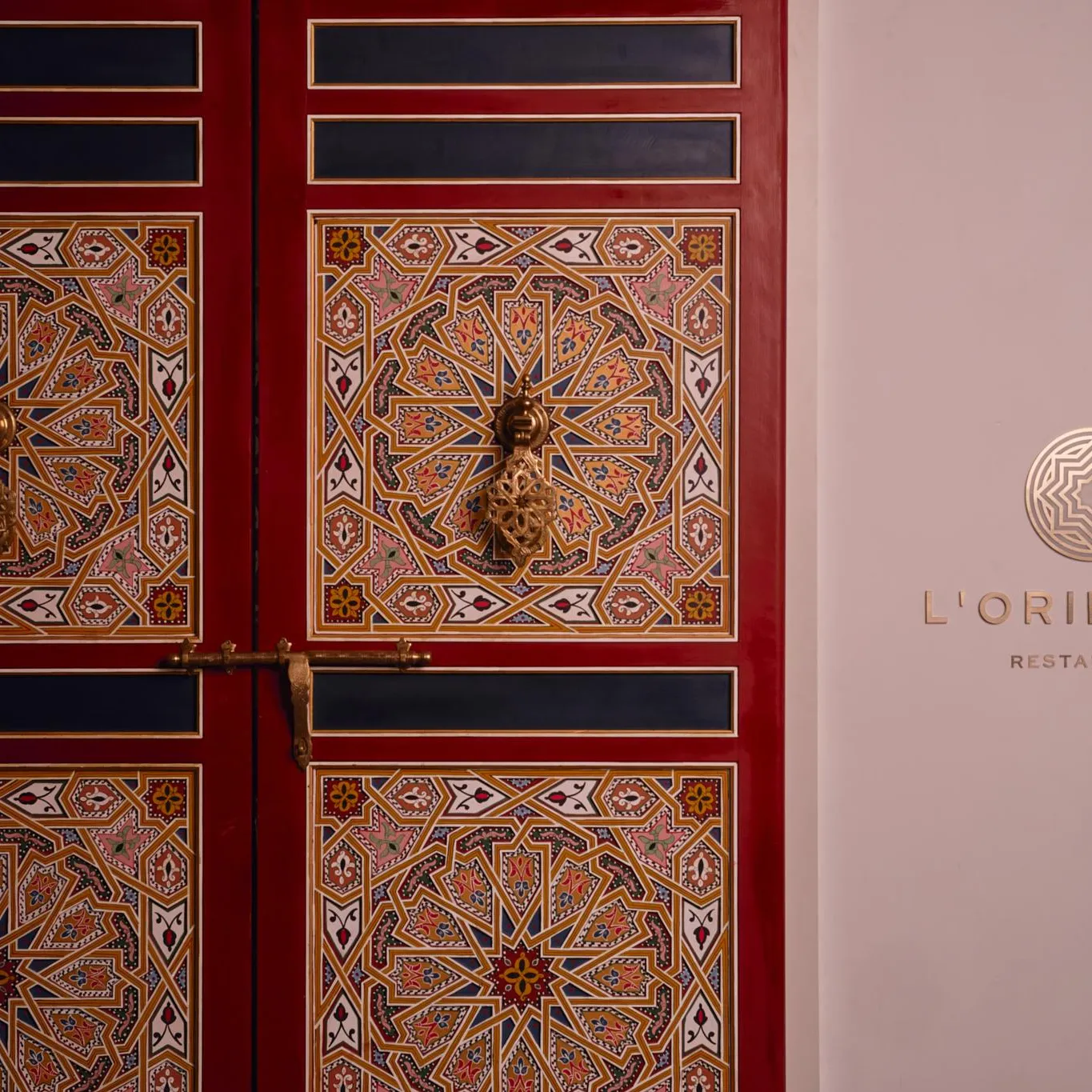 Porte décorée de motifs géométriques colorés avec la mention "L'ORIENTIN RESTAURANT" à côté