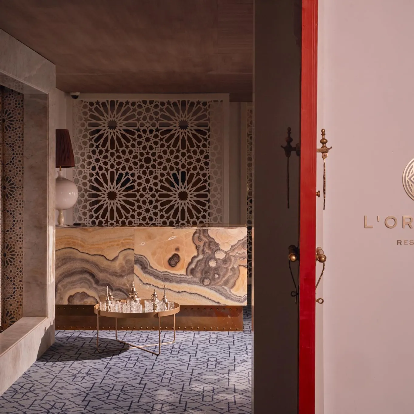 Vue de l'intérieur d'un restaurant nommé L'Orientin, avec une décoration murale géométrique et un comptoir en marbre