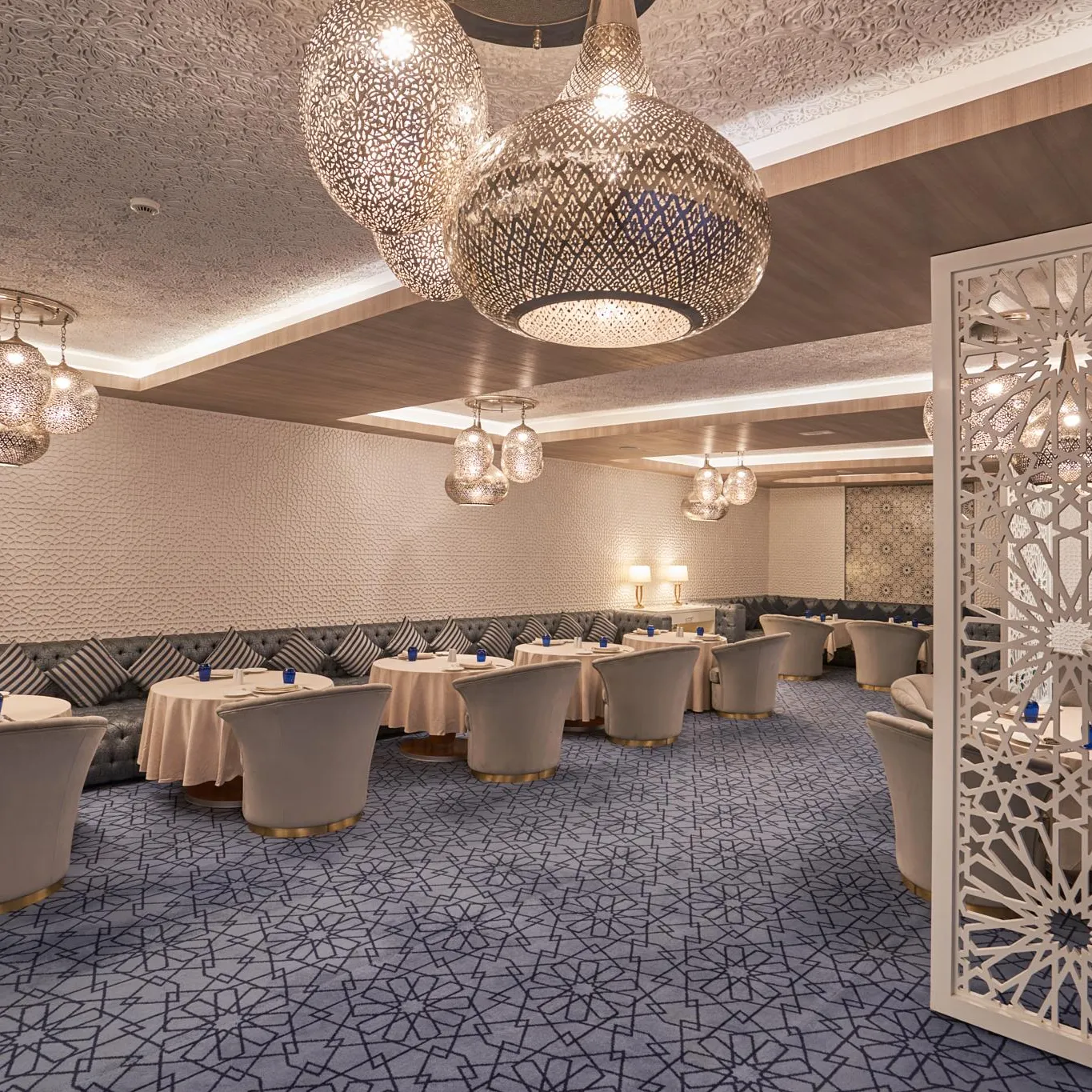 Restaurant élégant avec tables rondes, chaises assorties, luminaires métalliques et motifs géométriques sur les murs et le sol