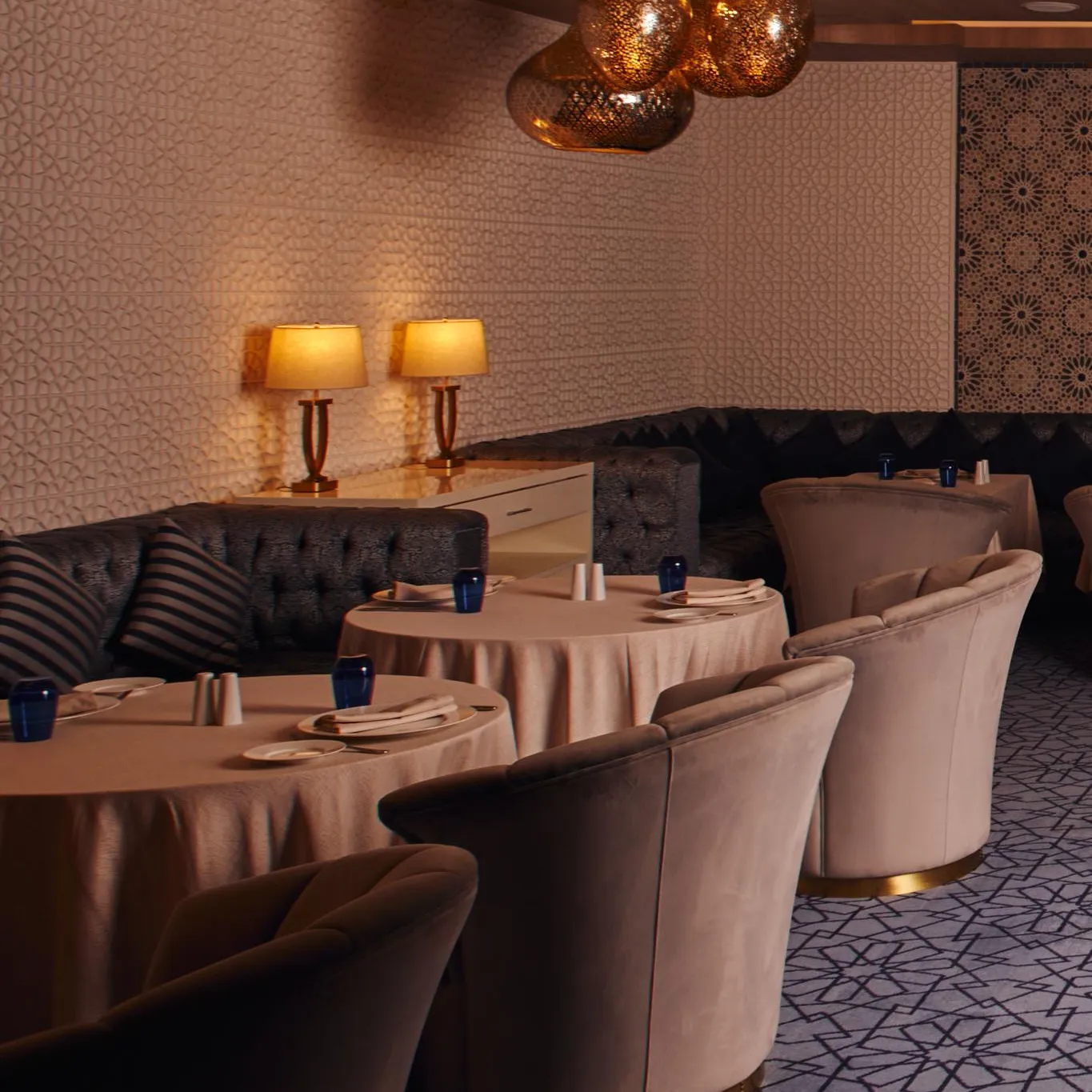Un restaurant élégant avec des tables rondes recouvertes de nappes roses, des chaises rembourrées et des luminaires suspendus