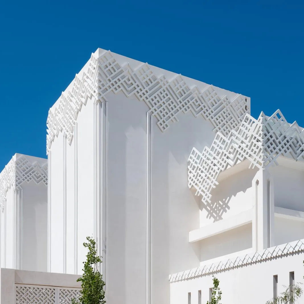 Bâtiment blanc avec des motifs géométriques en relief sur la façade et le toit, sous un ciel bleu clair