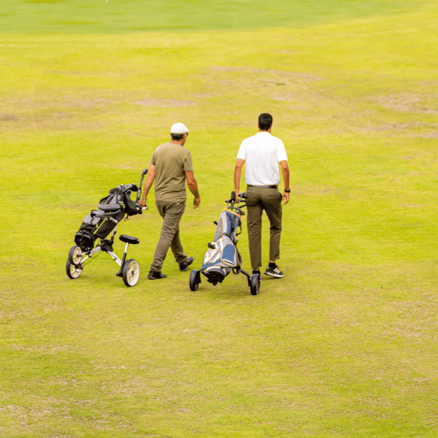 Deux personnes marchent sur un terrain de golf en poussant des chariots de clubs