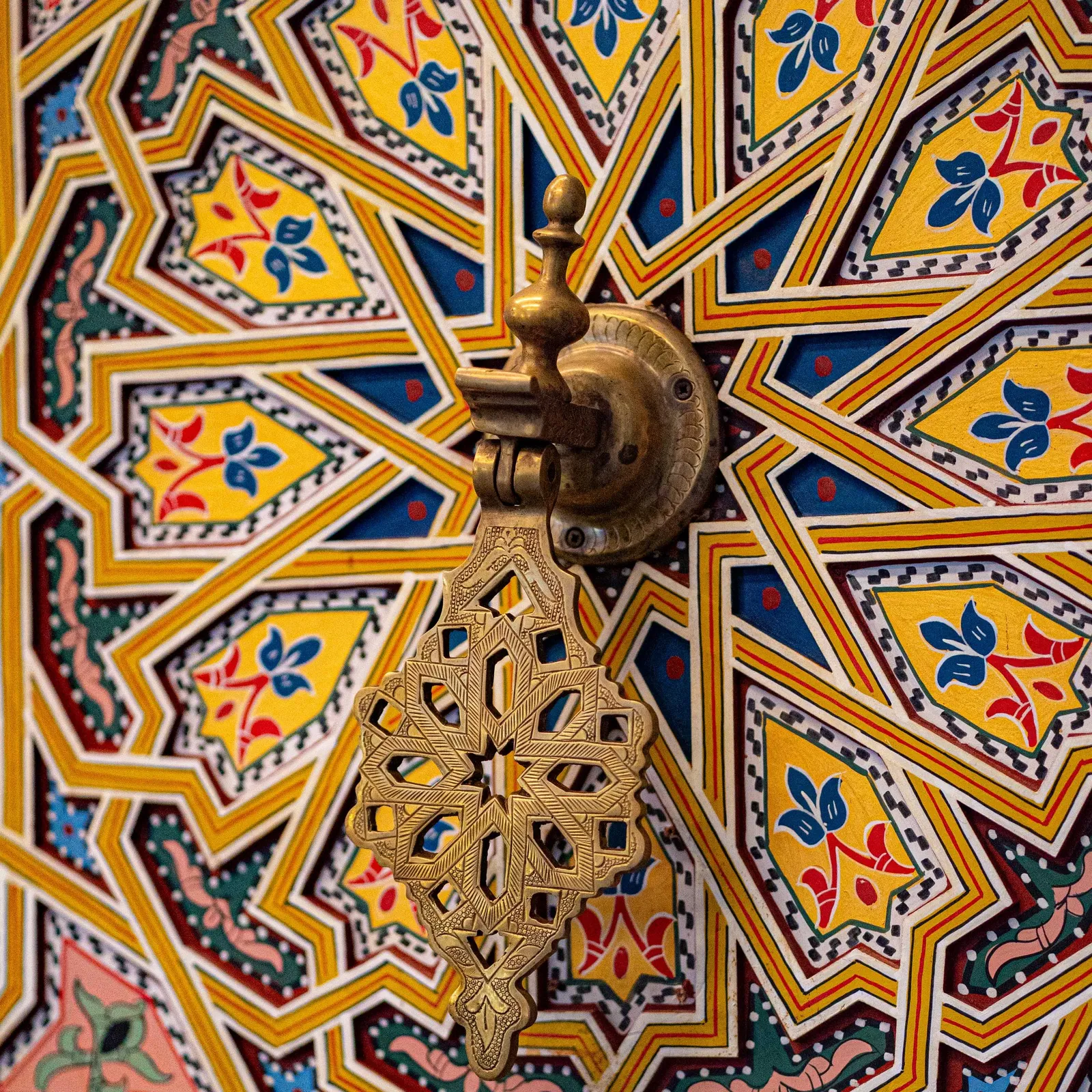 Un chandelier en métal avec une croix éthiopienne est suspendu à un plafond orné de motifs géométriques colorés