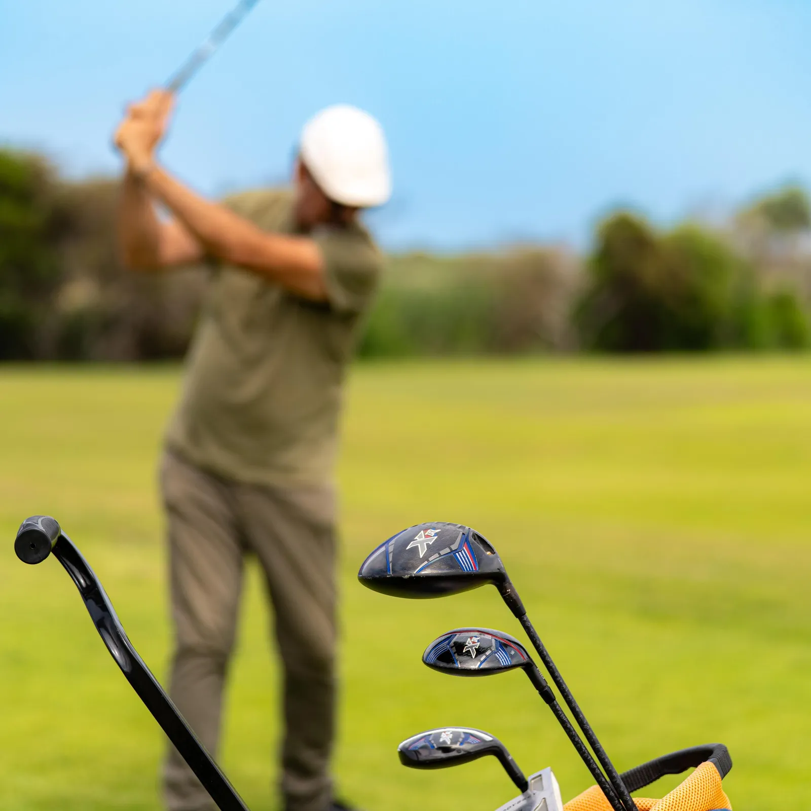 Un golfeur en action sur un green avec un sac de clubs à proximité