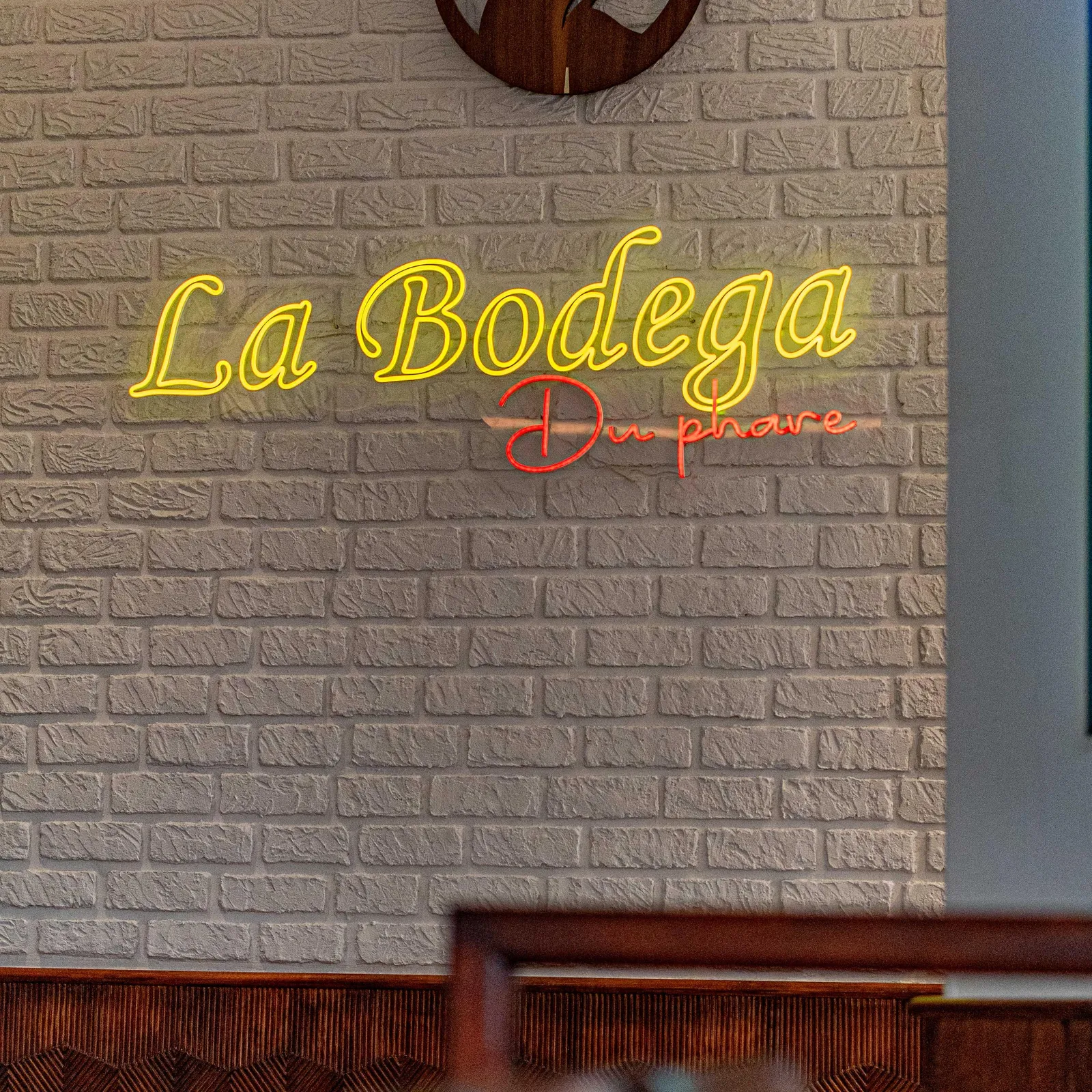 Mur de briques avec l'enseigne lumineuse "La Bodega" et un logo de taureau au-dessus