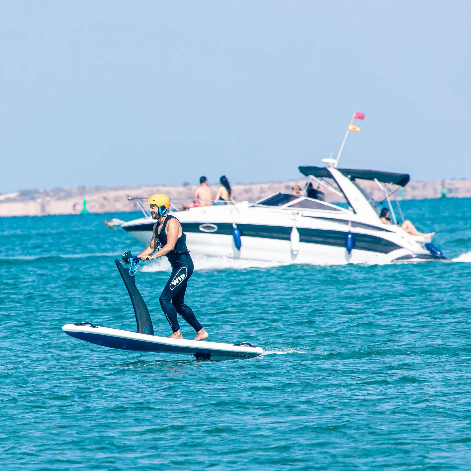 Une personne fait du paddle avec une pagaie dans la mer, un bateau est visible en arrière-plan