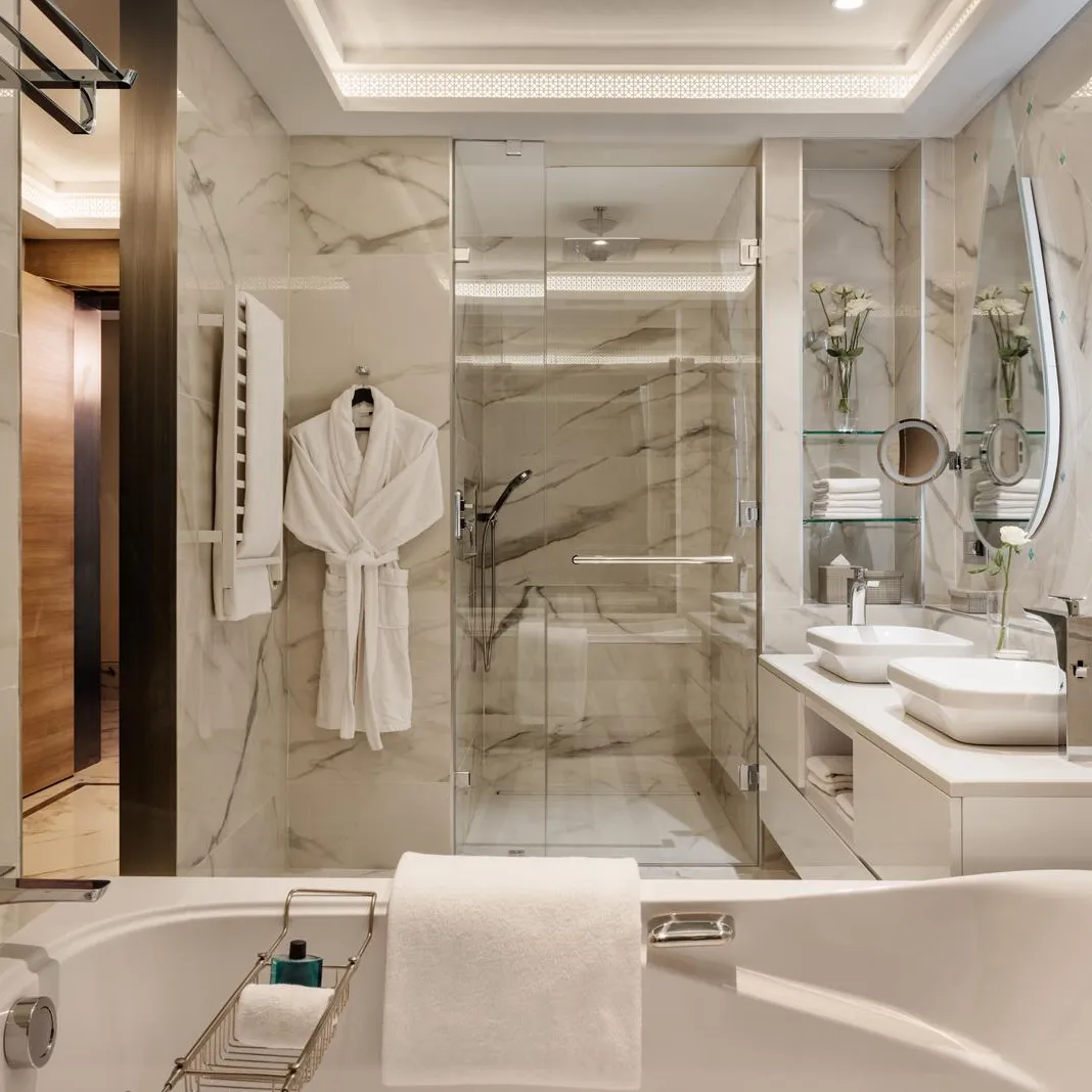Salle de bain luxueuse avec baignoire, douche en verre, double vasque et miroir rond éclairé
