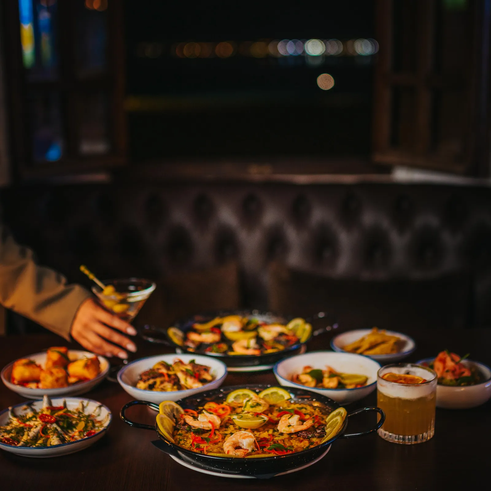 Un ensemble de plats variés et de boissons posés sur une table dans un restaurant sombre