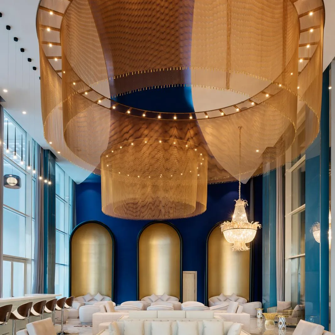 Un salon luxueux avec des canapés blancs, des tables basses et un plafond décoré de tissus dorés et de lumières