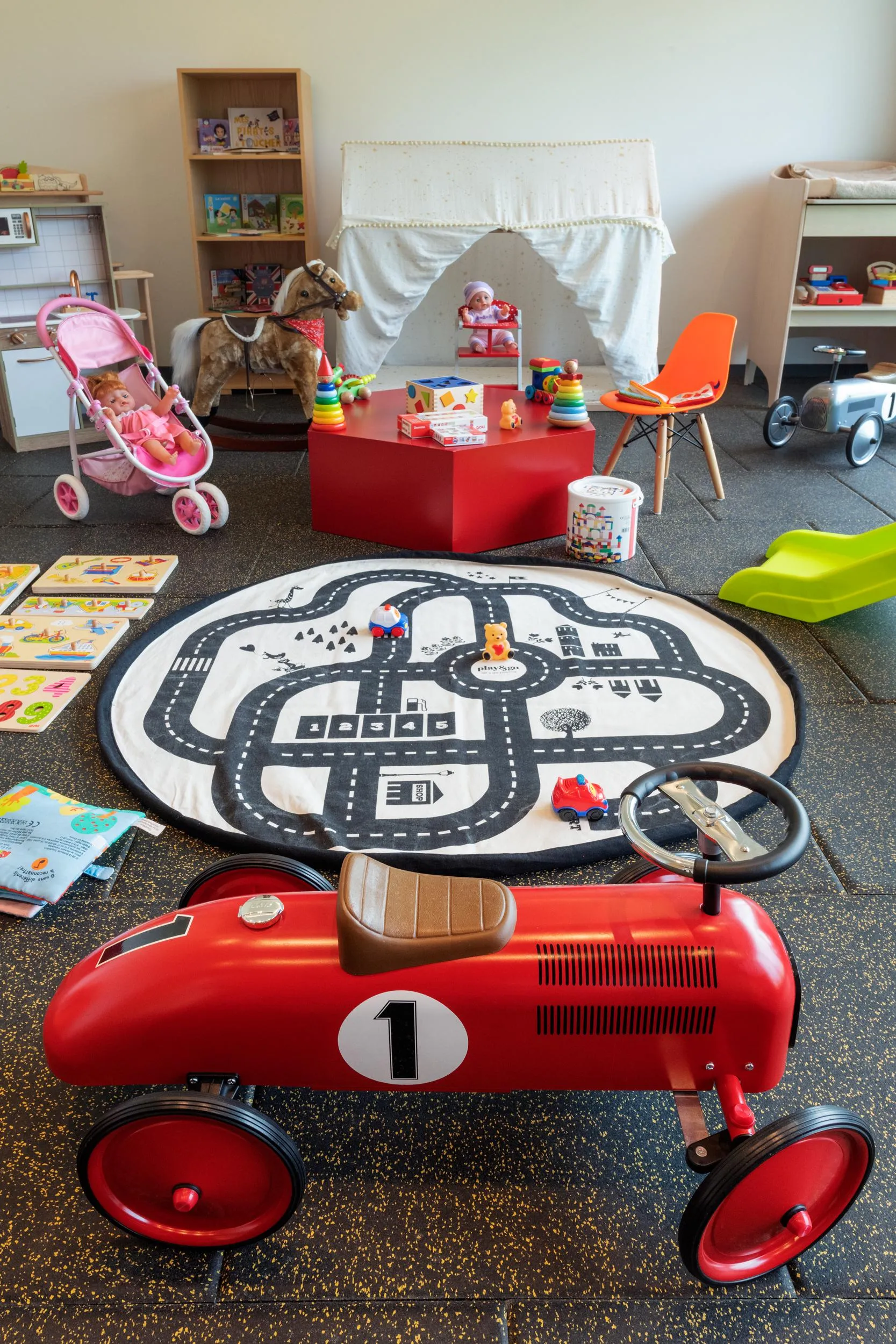 Child's room with toys, including a red car, a road mat, and a rocking horse