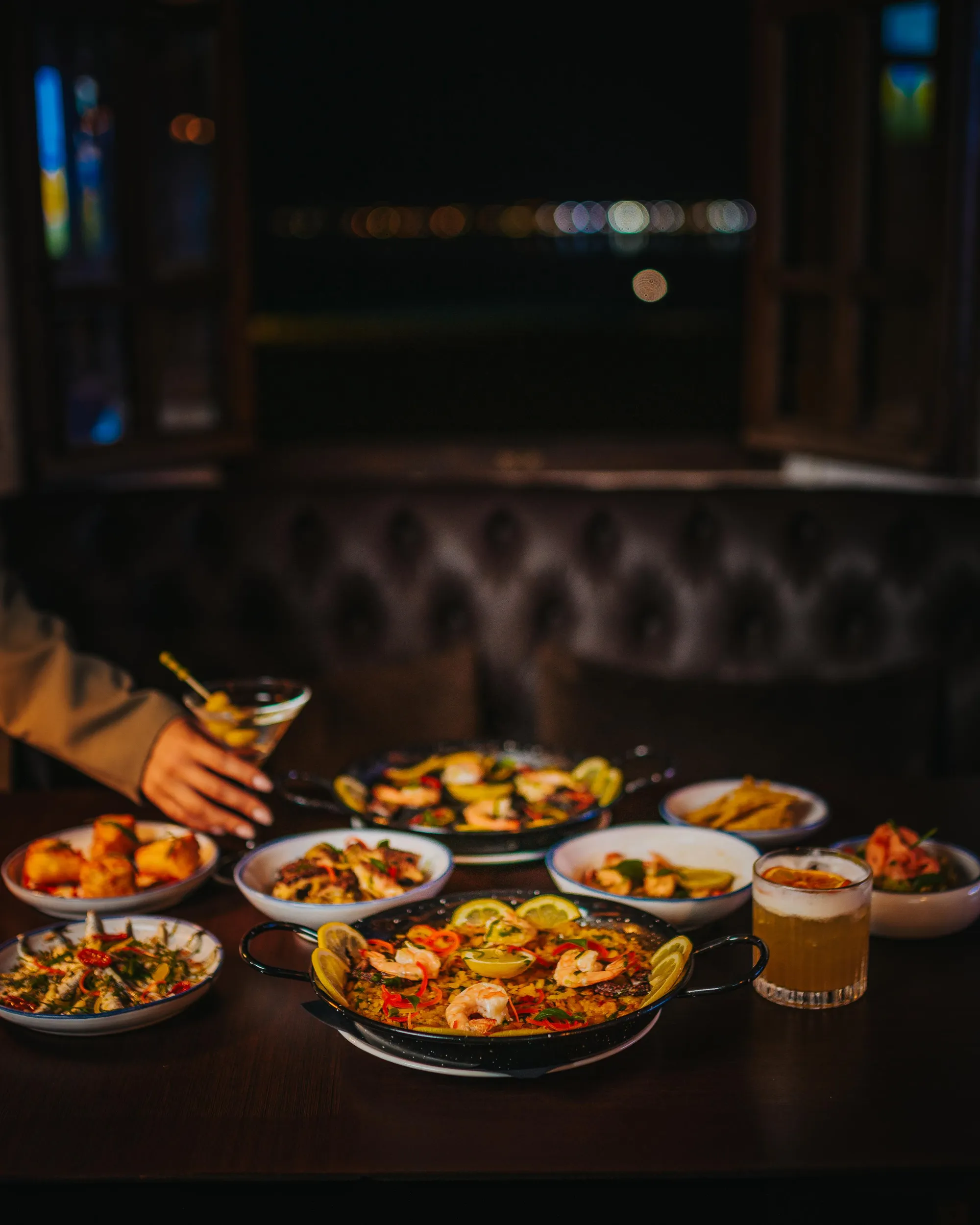 Un ensemble de plats variés et de boissons posés sur une table dans un restaurant sombre