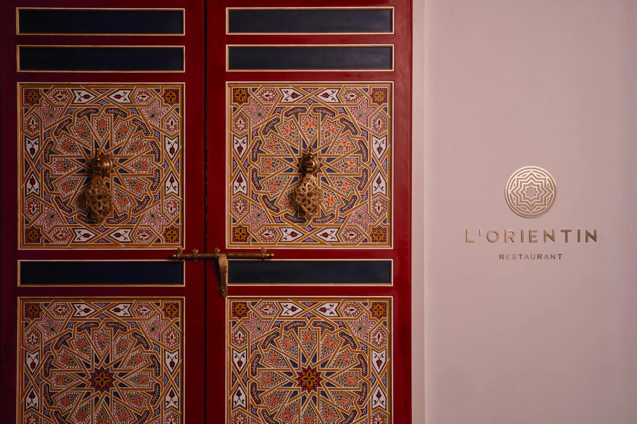 Door decorated with colorful geometric patterns with the inscription "L'ORIENTIN RESTAURANT" next to it