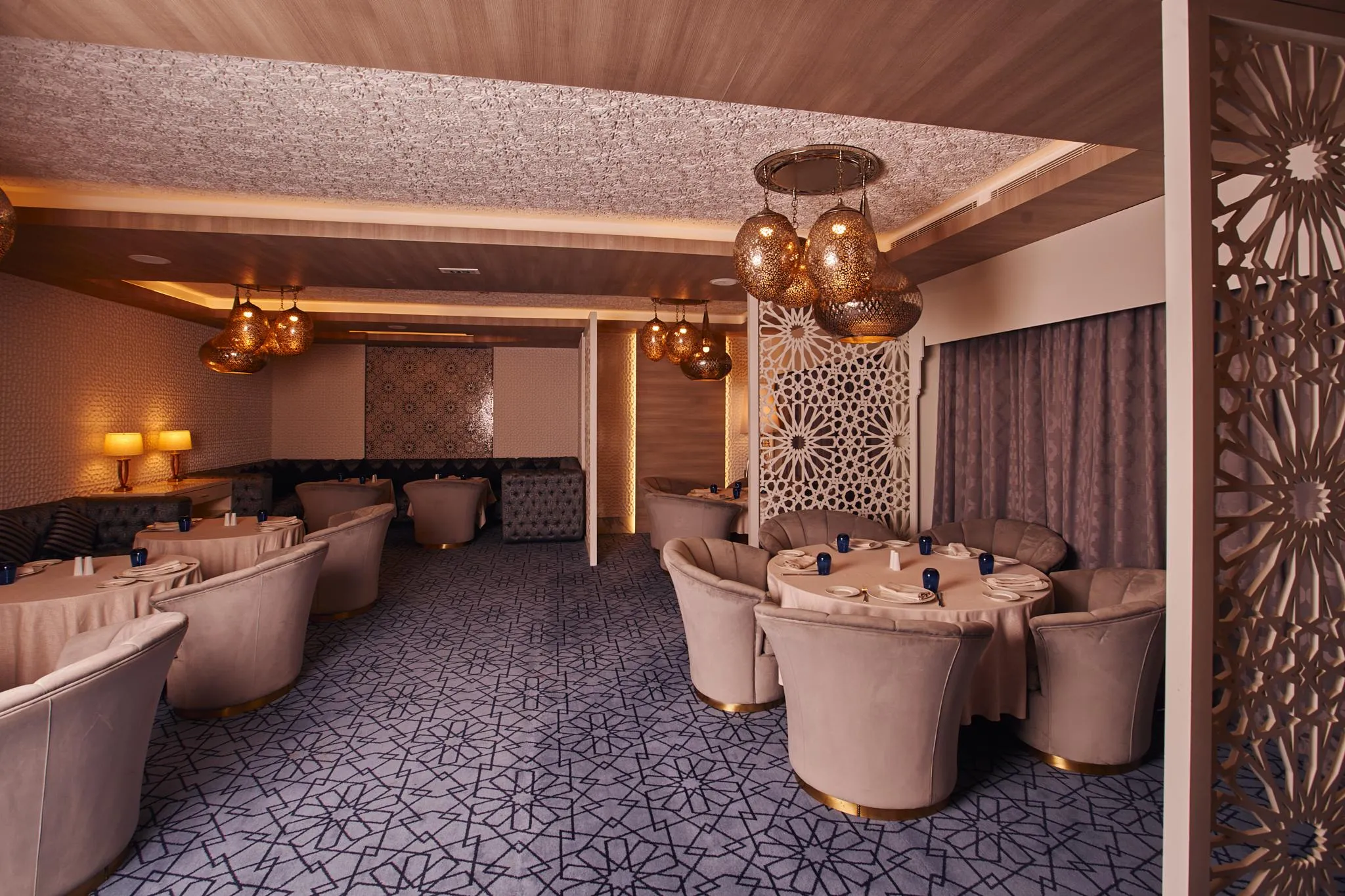 Elegant restaurant room with round tables, velvet pink upholstered chairs, and hanging light fixtures