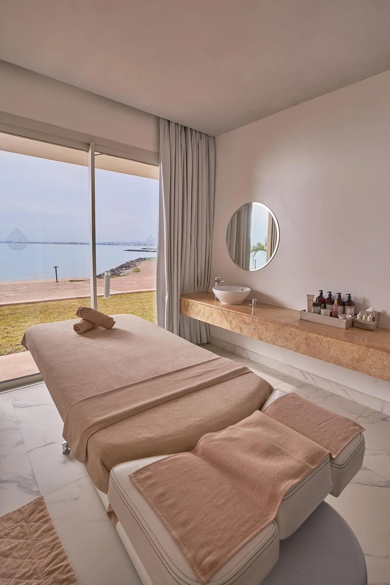 Massage room with two treatment tables, a sink, and a sea view