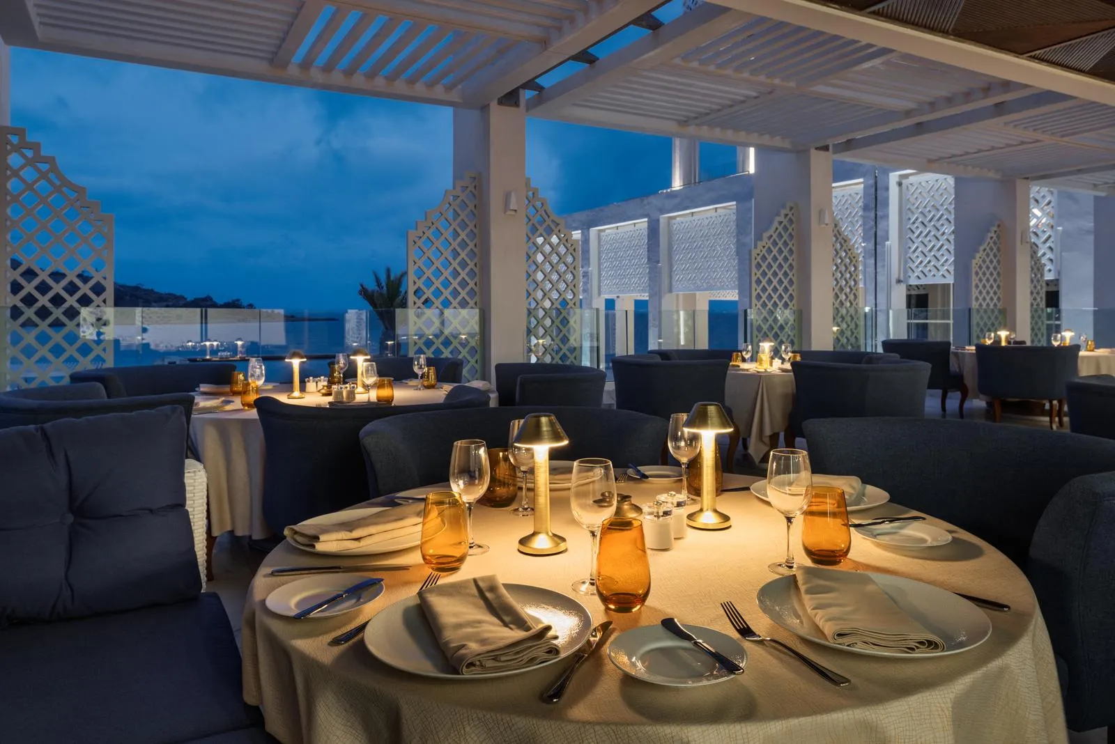 Elegant restaurant with set tables and sea view at sunset