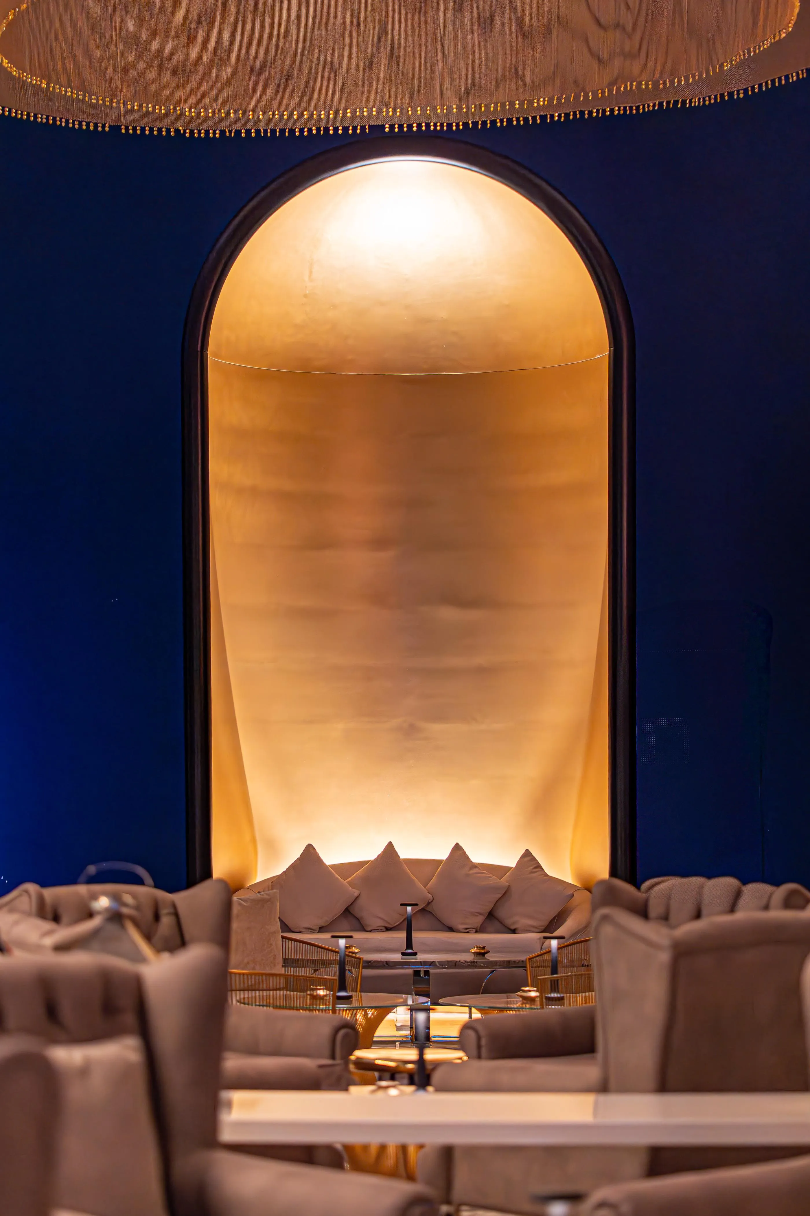 An interior space with sofas and a coffee table, lit by golden light through an arch.