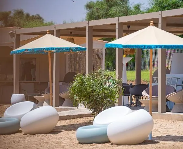 An outdoor space with white and blue sofas, blue fringed umbrellas, and wooden pergolas.