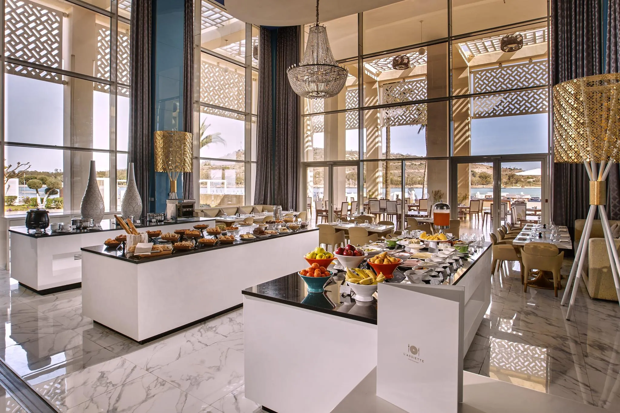 Restaurante elegante con buffet de desayuno, ventanas grandes y vista al mar