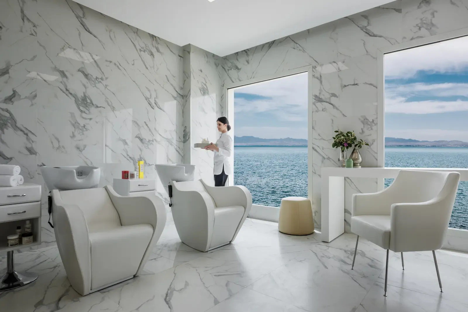 Luxurious hair salon with sea view, a person holding a tray near the hairdressing chairs