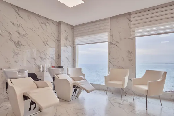 Modern hair salon with hairdressing chairs and seats, sea view through large windows